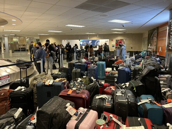 Bags at an airport and people in line.