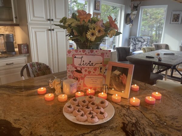 Candles lit on a table with cookies and flowers.