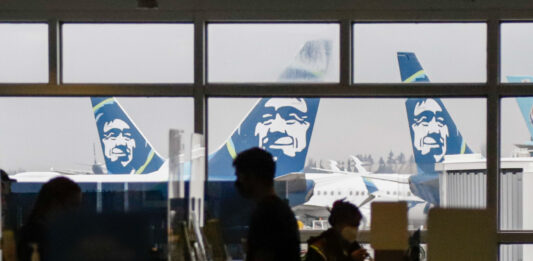 several Alaska Airlines planes parked at airport gates