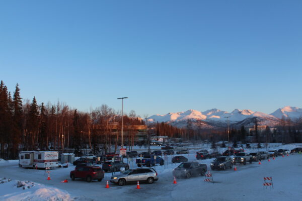 A line of cars snaking through a parking lot with some mountains in the background