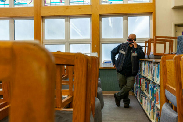 A person stands in a library on a cell phone