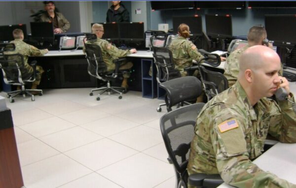 People wearing military camo gear in a room around desks