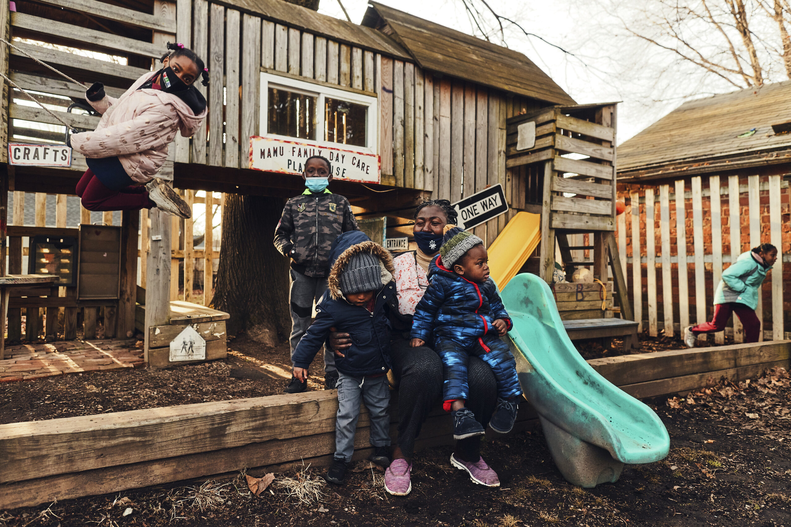 A group of small children in masks play near a playground