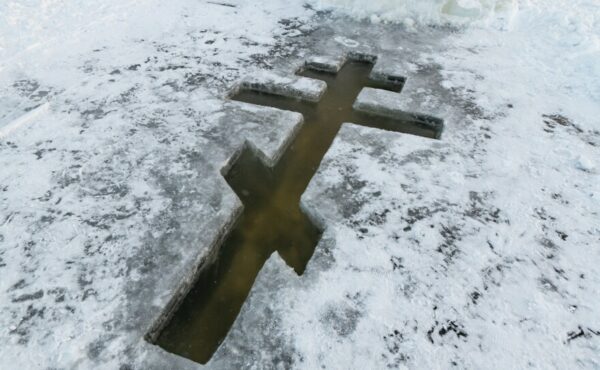 A cross carved into river ice reveals water below the surface..