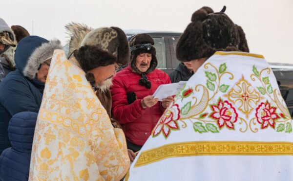 A man dressed in winter clothes reads from a piece of paper.