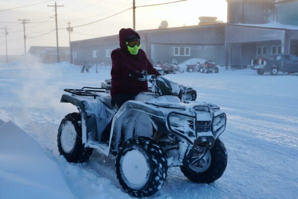 a person riding an ATV through the snow in front of a school