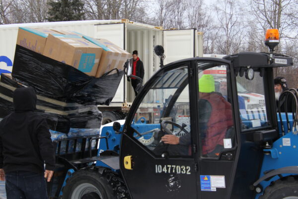 A forklift drives pallettes into a Matson shipping container (
