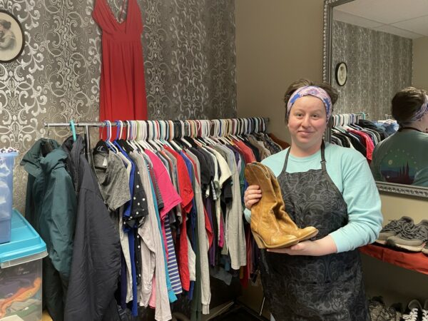 A woman in an apron standing next to a rack full of clothes