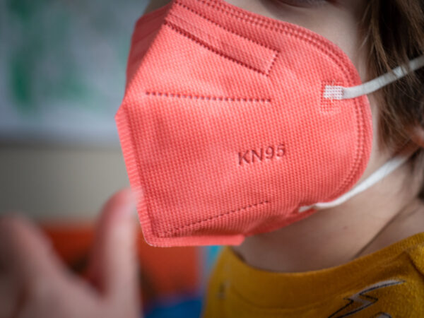 A close up of a red KN95 mask on a person's face