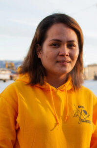 A woman standing outside in a yellow Bethel hoodie