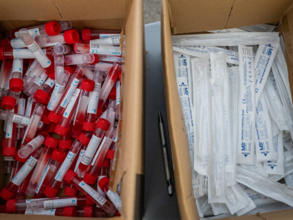 Vials of testing fluid and packages of nose swabs in boxes on a table