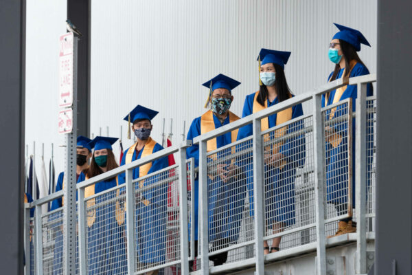 Students stand in a line in caps and gowns