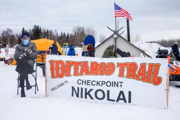 A cut-out Bernie Sanders next to a sign that says: Welcome to Iditarod Trail checkpoint Nikolai