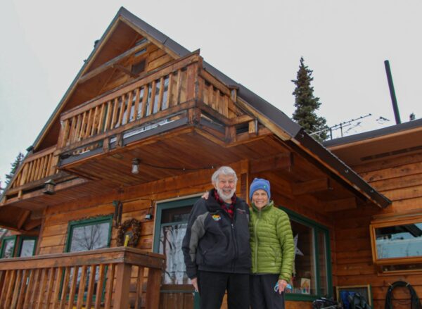A couple stands in front of a log home