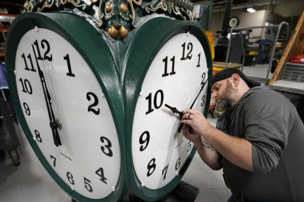 A clock technician adjusts the hands on a large outdoor clock under construction at Electric Time Company in Medfield, Mass, last year, just days before daylight saving time was set to end.