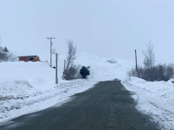 A huge pile of snow blocks a road