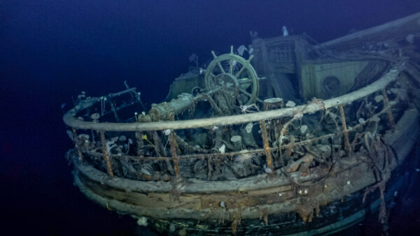 Underwater photo of the deck of a shipwreck, showing the ship's wheel