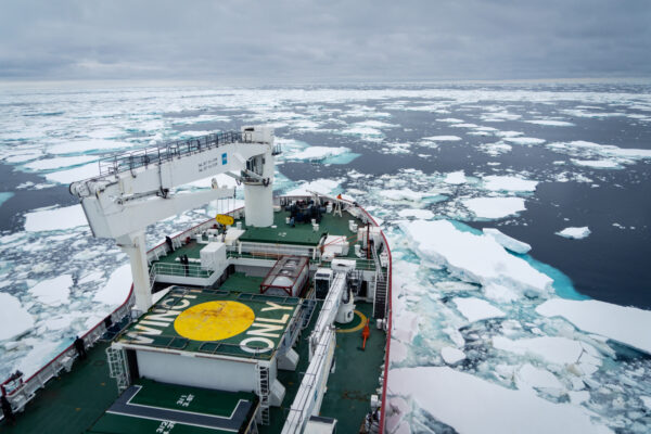 A modern research ship sailing through icy seas