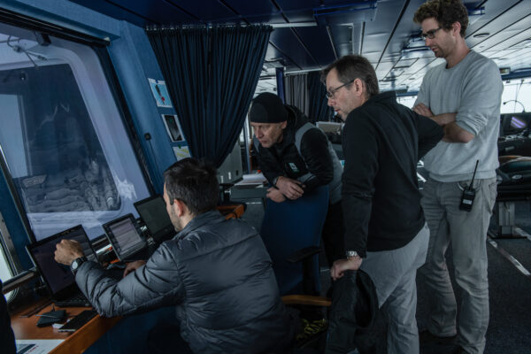 Four men in a ship staring at laptops