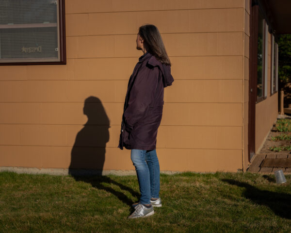 A woman seen in profile, with her shadow cast on the side of a house