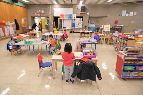 A preschool classroom with a few children sitting at tables