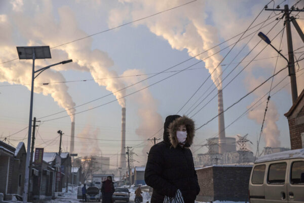 a person in a face mask walking near power plants