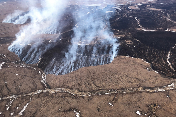 Aerial photo of a large fire burning in brown tundra