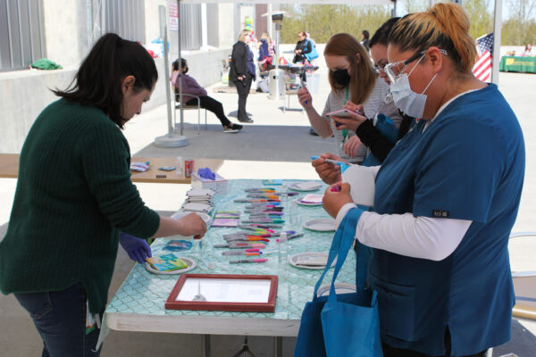 Healthcare workers paint tiles at a carnival as a part of nurses week.
