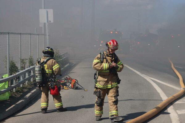 two firefighters on a roadway. the air is heavy with smoke