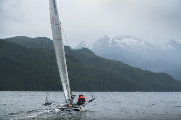 A sailboat on calm water with mountains in the background.