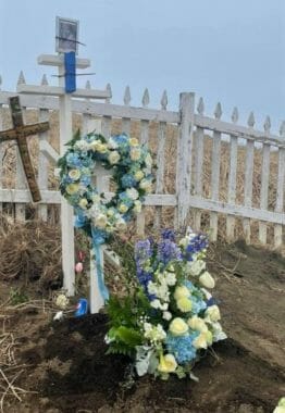 A grave with flowers and two crosses on it
