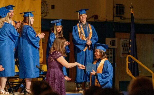 an adult gives a student a diploma