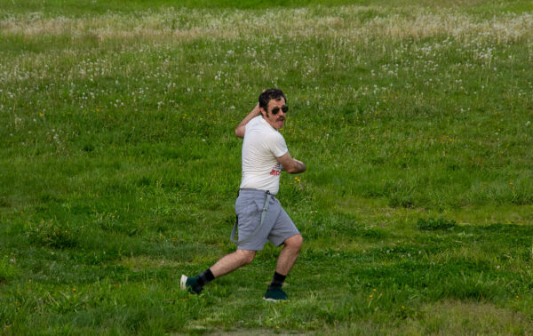 A man in sunglasses plays frisbee in a grass field.