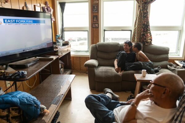 A family watching coverage of the fire in their living room with dense, smoky air visible outside