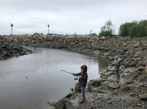 Two small children fishing in a narrow slough
