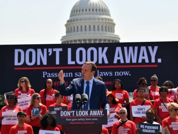 A rally with a banner that says "Don't look away" and the U.S. Capitol behind it