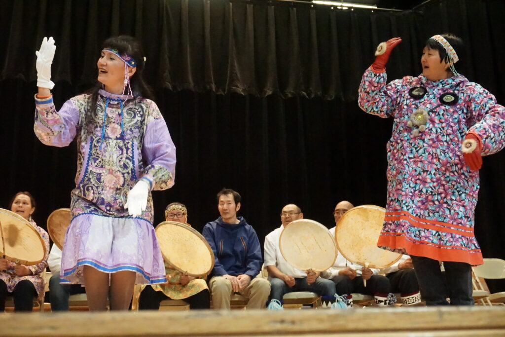 Interior: Women perform a traditional Inuit dance.