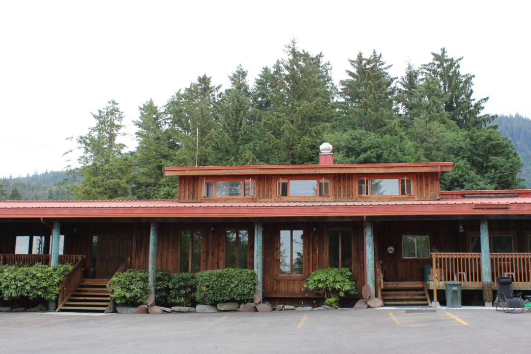 An exterior view of a cedar building with a red roof