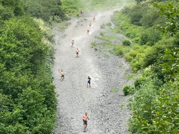 people run down a steep gravel mountainside