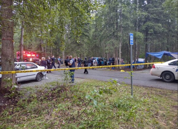 Police cars and yellow tape at a crime scene in the forest
