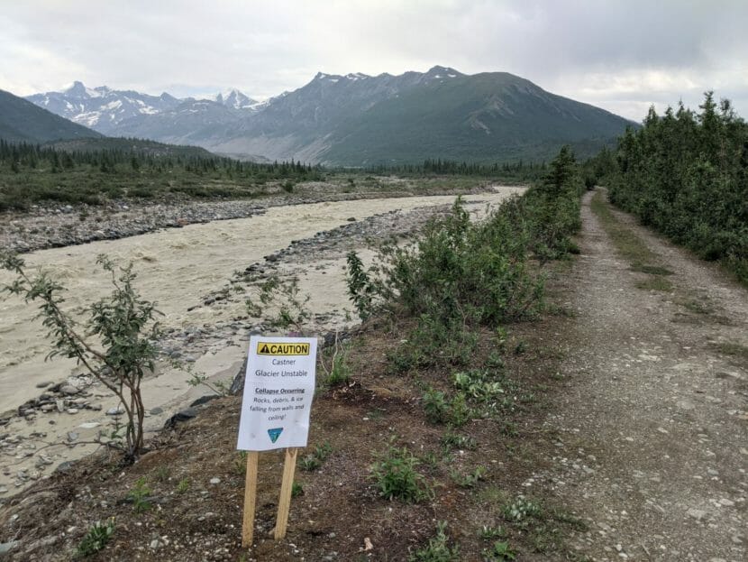 A sign warning about the unstable glacier on the bank of a creek