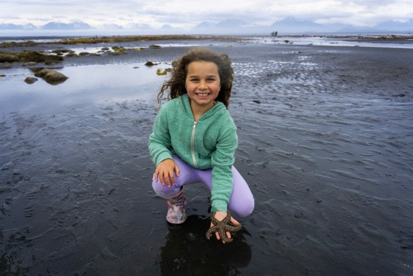 Exterior: A girl holding a starfish in a tidepool