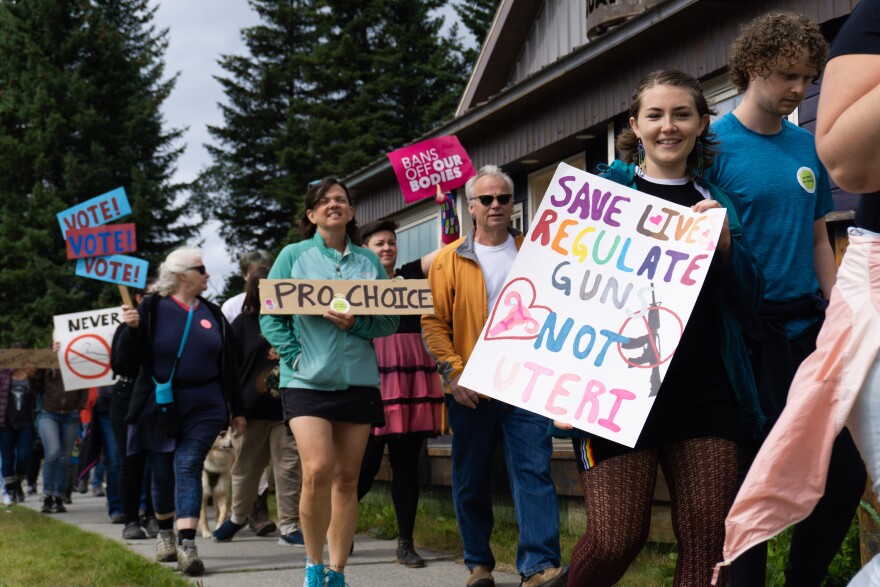 People hold signs saying "pro choice" and "regulate guns, not uteri"