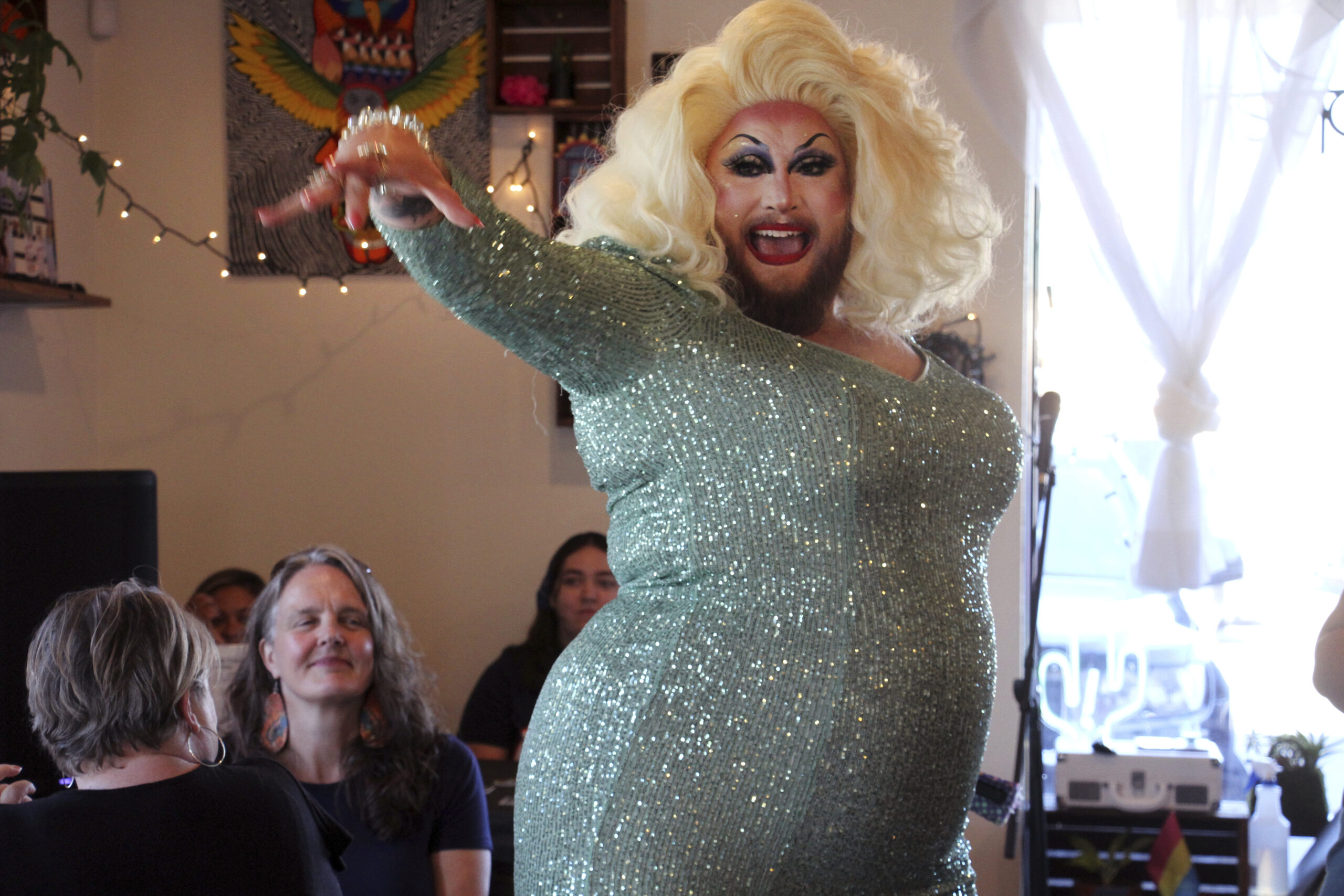a person cheers while wearing a blonde wig and sparkly body suit