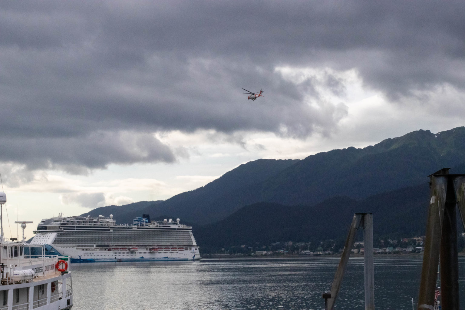 a helicopter flies near a cruise ship on an overcast day