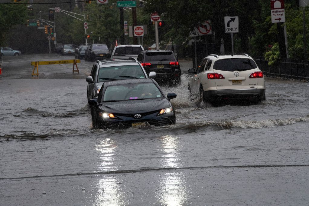cars drive through flooded street