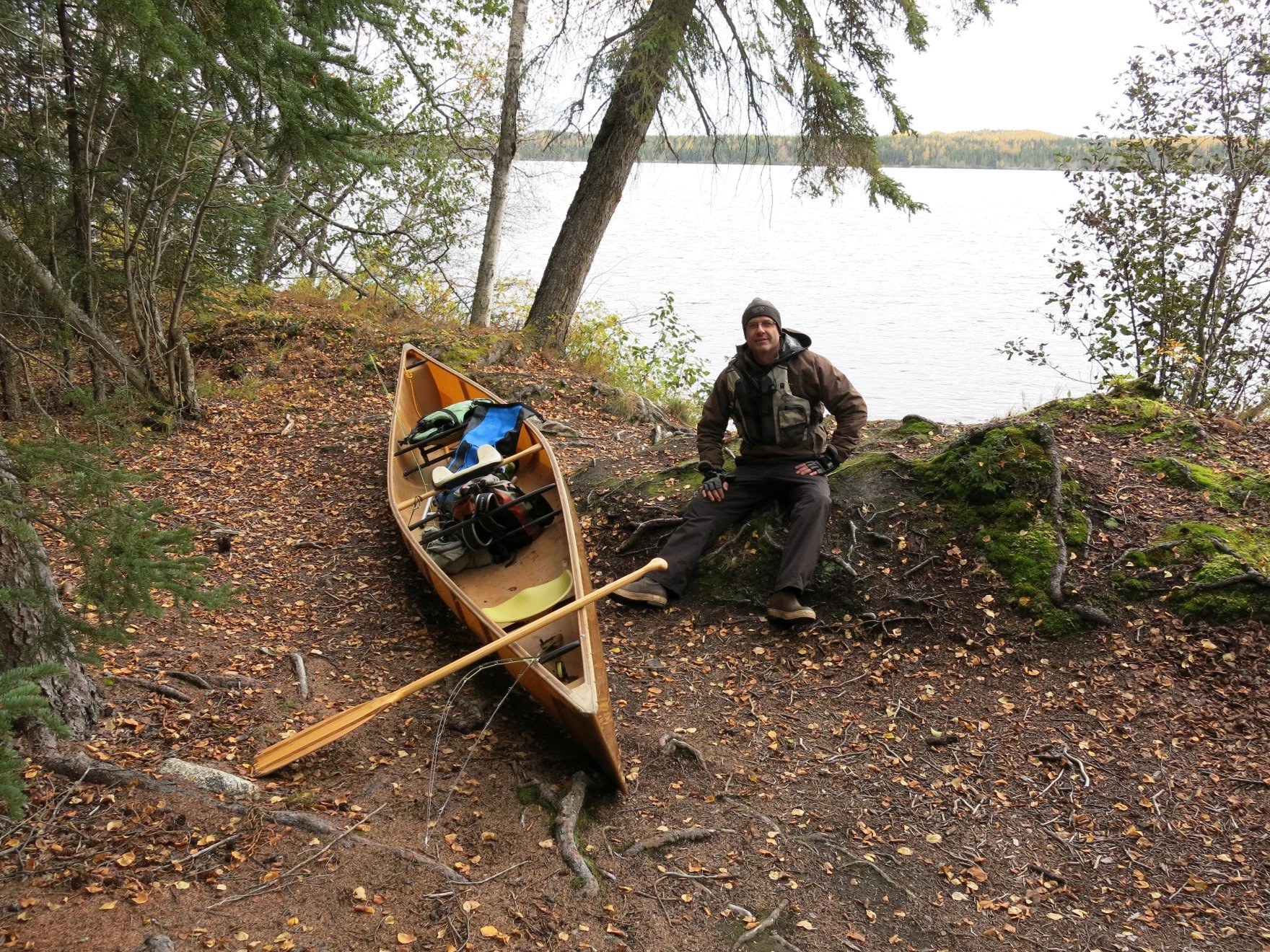 a man sits next to a canoe outside