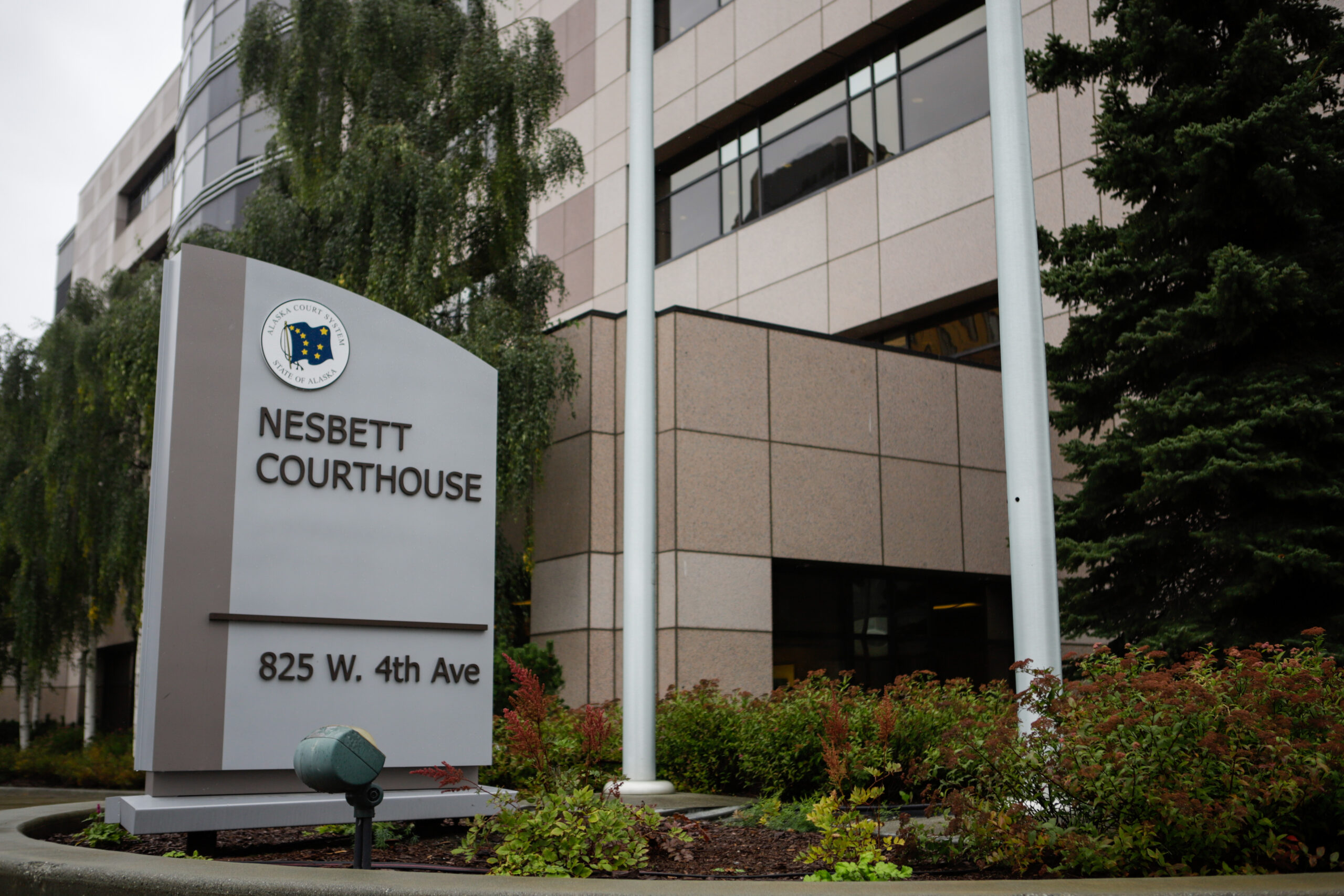 A sign, in a small garden with shrubs, reads "Nesbett Courthouse."