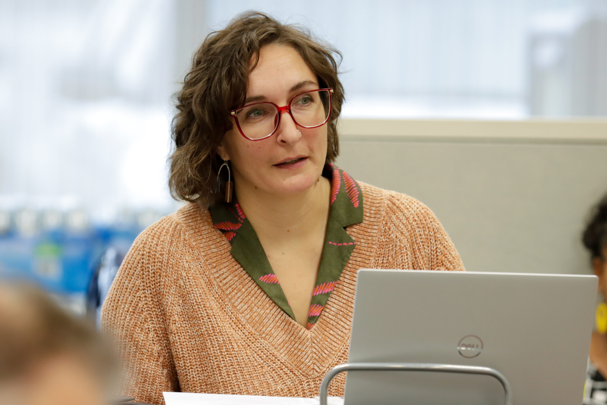 A female pinch a pinkish sweater and reddish glasses