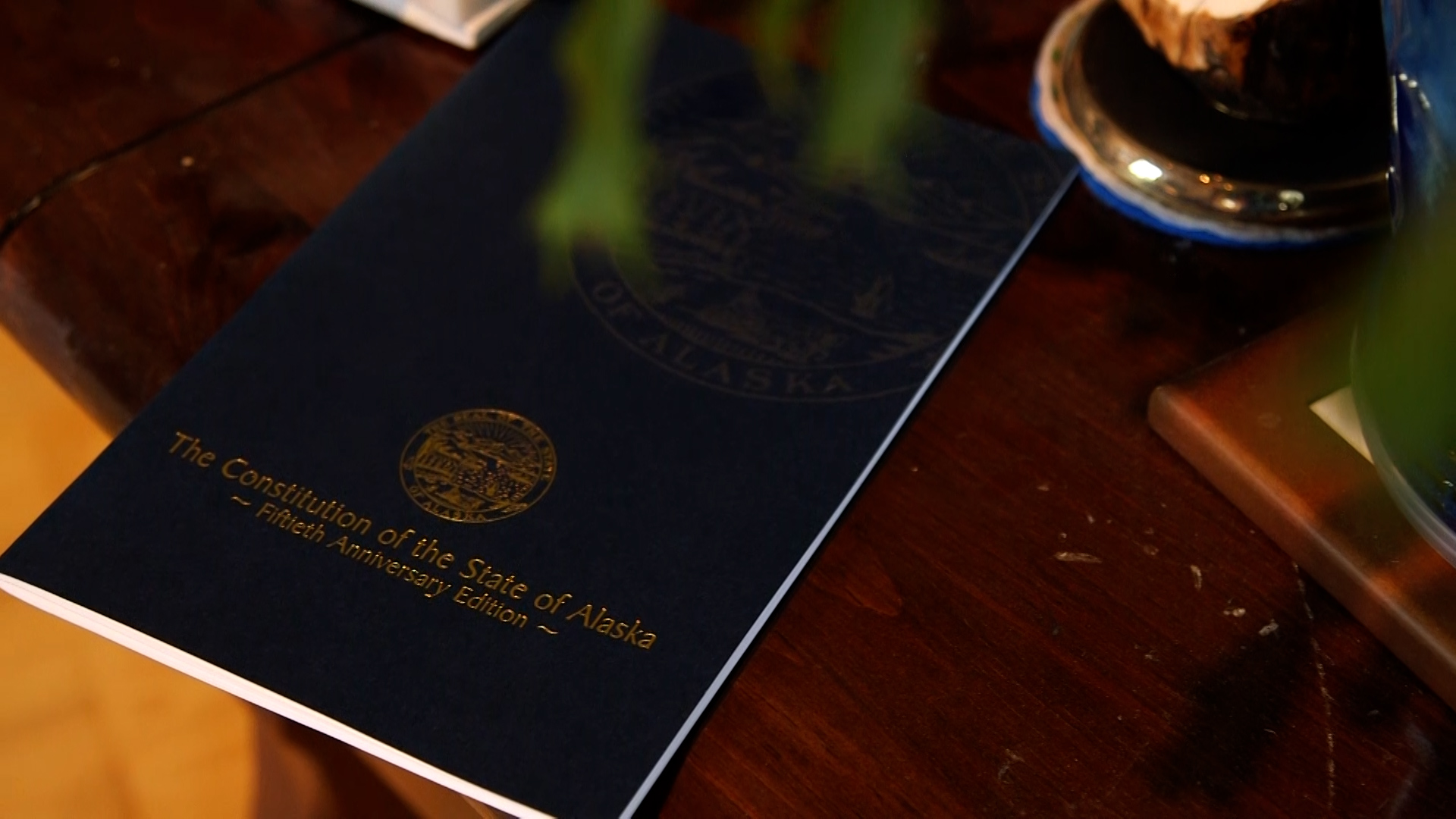 A 50th anniversary copy of the Alaska State Constitution sits on the top of a table.
